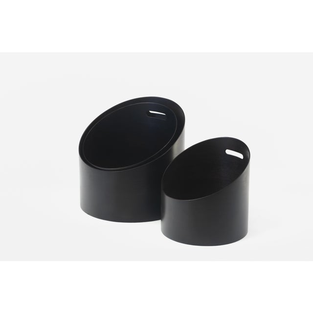 Open, slanted wooden containers made of curved beech wood, finished with a dark brown aniline finish. The practical handle...