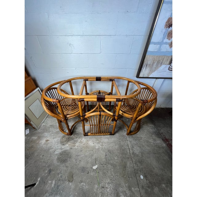 This lovely little rattan and cane set made in the late 1970s includes a small table with an oval glass top and two chairs...