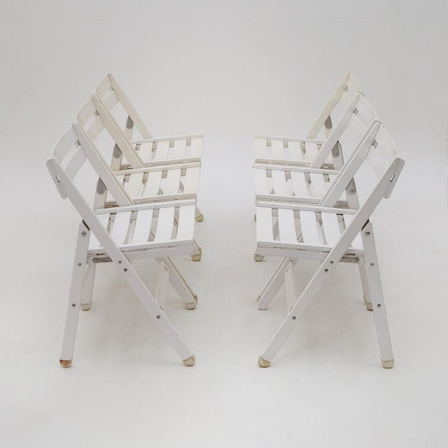 A set of six folding outdoor chairs produced by Reguitti in the 1970s, characterised by a white-painted wooden structure...