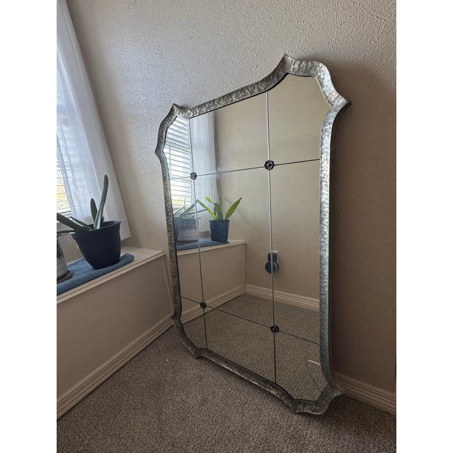 This Uttermost decorative wall mirror, featuring a striking hammered metal frame and classic vintage-inspired silhouette....