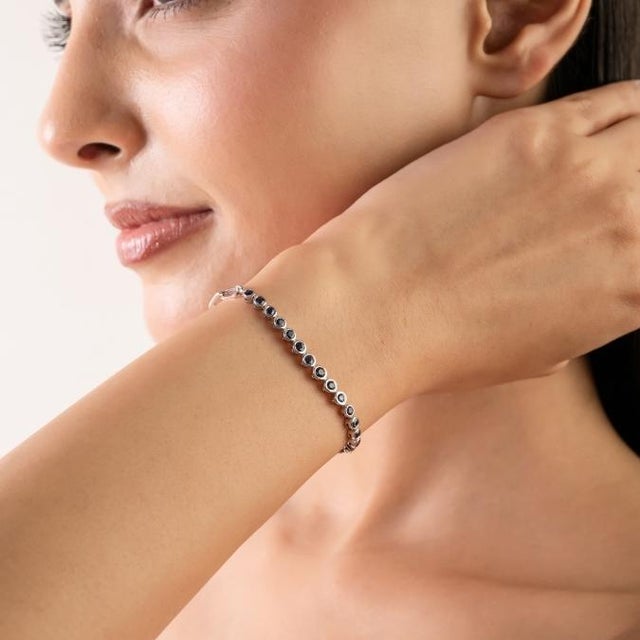 This elegant thandcrafted tennis bracelet features 15 round cut blue sapphire totaling 0.97 carats, set in rich 18k white...