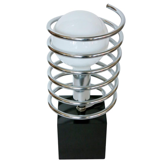 This Modernist spring table lamp features a black steel cube with a chrome socket surrounded by a large chrome coil...