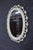 Oval wall mirror featuring an elegant pierced-cut frame with repeating scroll and fleur-de-lis motifs. Finished in white...