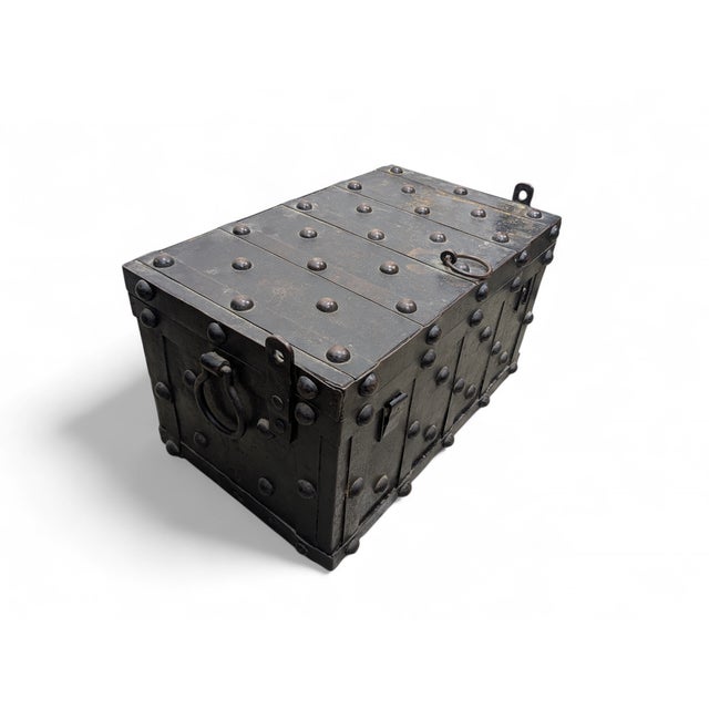An imposing chest made of heavy wrought iron, featuring a structure reinforced with transverse bands and dense round-...