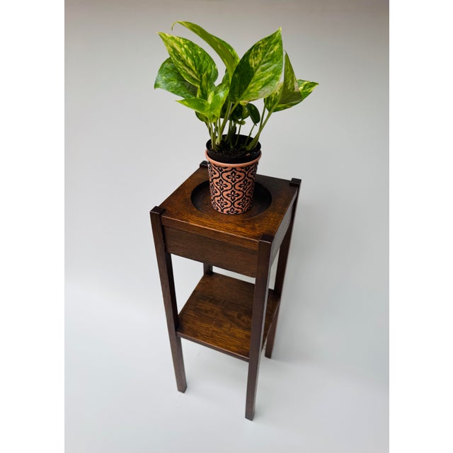 A handsome antique Arts & Crafts oak fern stand dating to the early 20th century. Built from beautifully grained oak with...