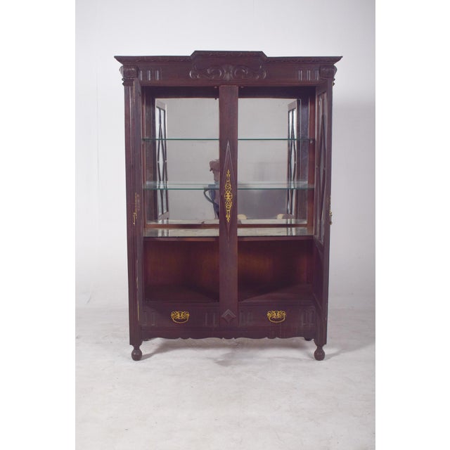 Dutch-style china cabinet with brass fittings. In dark wood with rich and striking decoration, of obvious Dutch...
