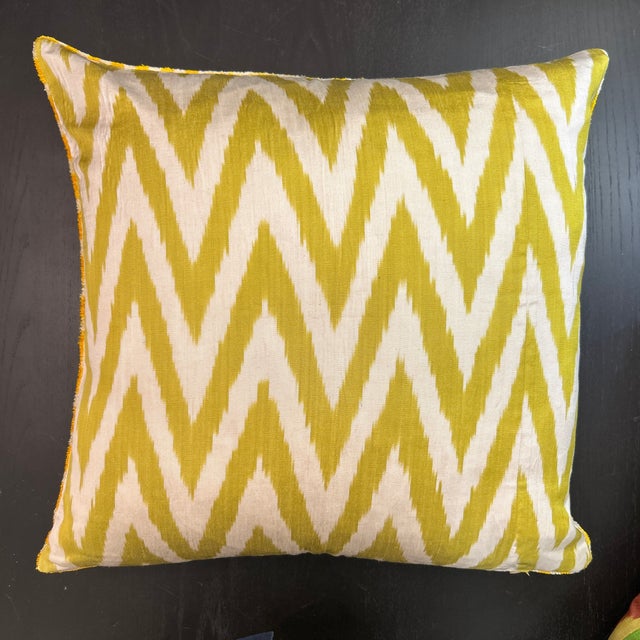 Woven ikat pillow in a soft green/gold chevron pattern on an off-white background. The reverse is velvet with a geometric...