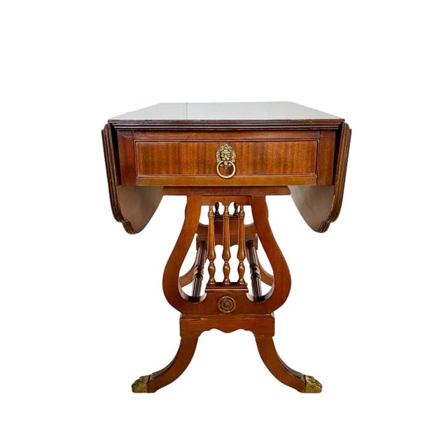 A vintage 1940's English Regency style mahogany drop-leaf accent or breakfast table with single drawer. Featuring a...