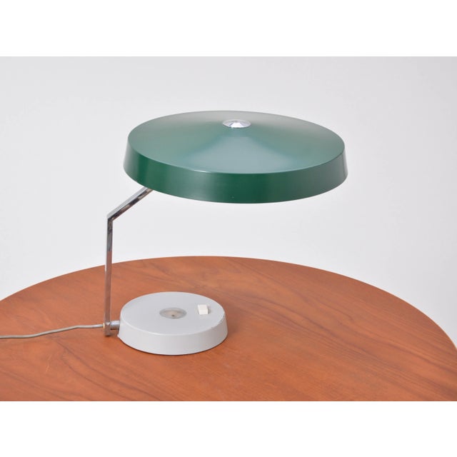 This desk lamp was produced in Germany in the 1960s. It is made of metal. It has three bulbs and the shade is rotable into...