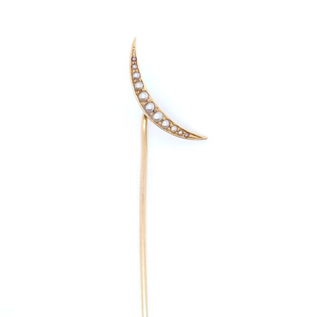 A fine antique gold and pearl pin. In the form of a crescent moon. In 14k gold. Set with 10 small seed pearls. Marked to...