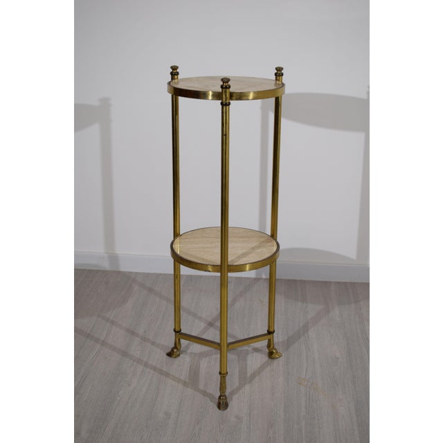 Elegant Italian-made gueridon table, dating back to the 1940s. Crafted from brass with a double circular travertine marble...