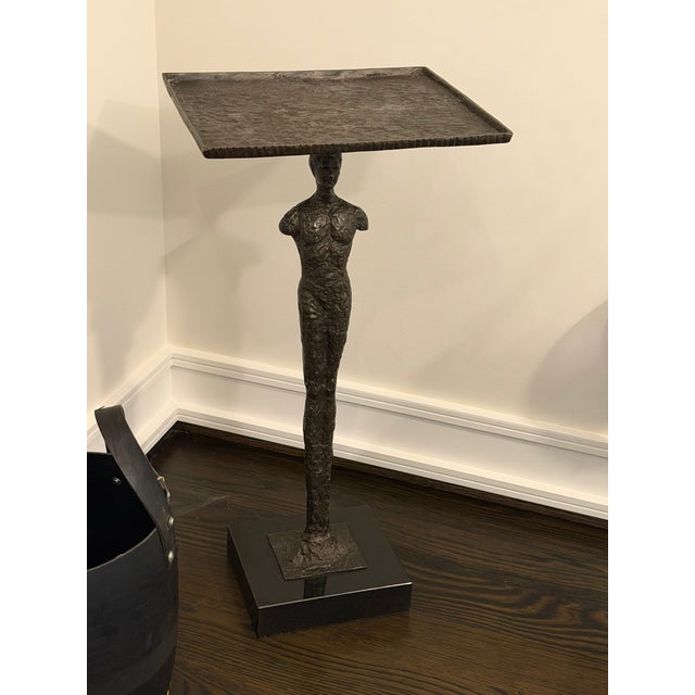A dramatic Giacometti‑style sculptural side table by Global Views, blending functional furniture with expressive modern...