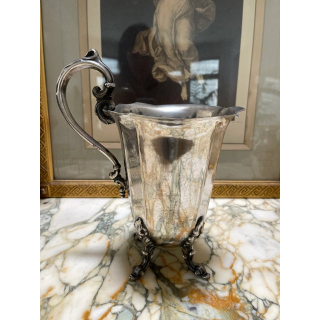 Vintage silver plated brass base pitcher with fluted style legs. Marking on the bottom is hard to make out but it looks...
