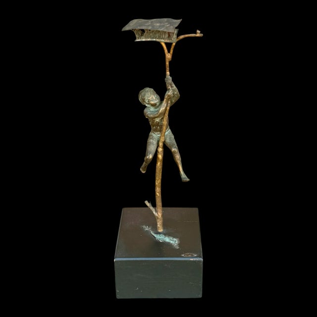A vintage bronze sculpture of a boy climbing a tree by mid-century artist Curtis Jere, signed and dated 1970. This...