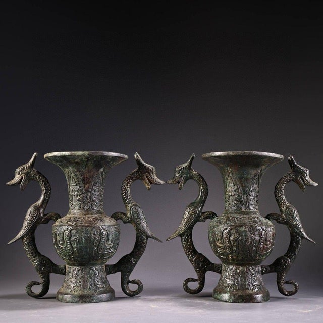 A striking pair of Chinese archaistic bronze vases. Each vase features a flared mouth and a bulbous body, decorated with...