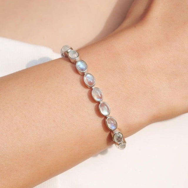 This exquisite tennis bracelet is crafted in 925 sterling silver and set with 24 natural oval-shaped rainbow moonstones,...