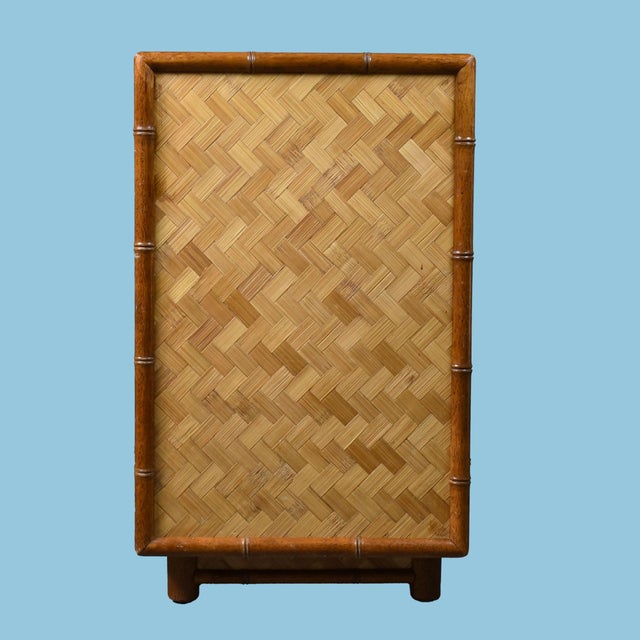 A substantial nine-drawer dresser in faux bamboo and wrapped rattan with woven drawer fronts and brass pulls. The warm...