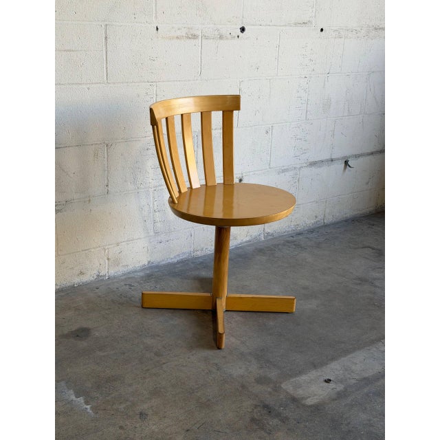 This striking swivel chair features a curved slatted backrest and smooth wooden construction. Crafted in Sweden, it...