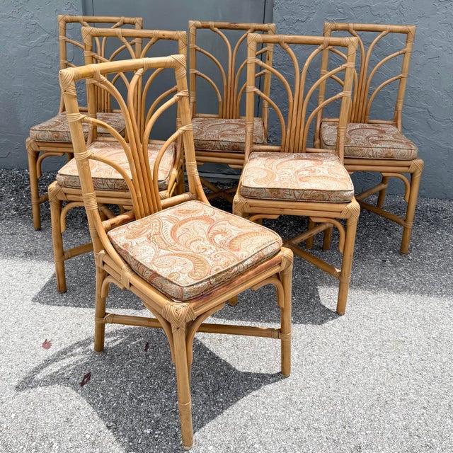 A charming set of six vintage dining chairs crafted from natural rattan with sculptural fan-shaped backs and decorative...