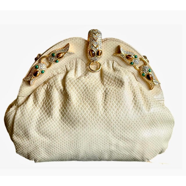 Chic and unique ivory toned karung leather pleated clutch with a gold tone frame embellished with crystal koi fish. Clasp...