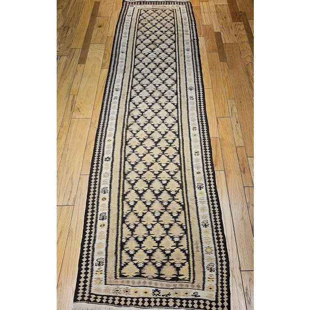 This authentic flat-woven Persian Qazvin kilim features a sophisticated allover pattern inspired by stylized flower buds—a...