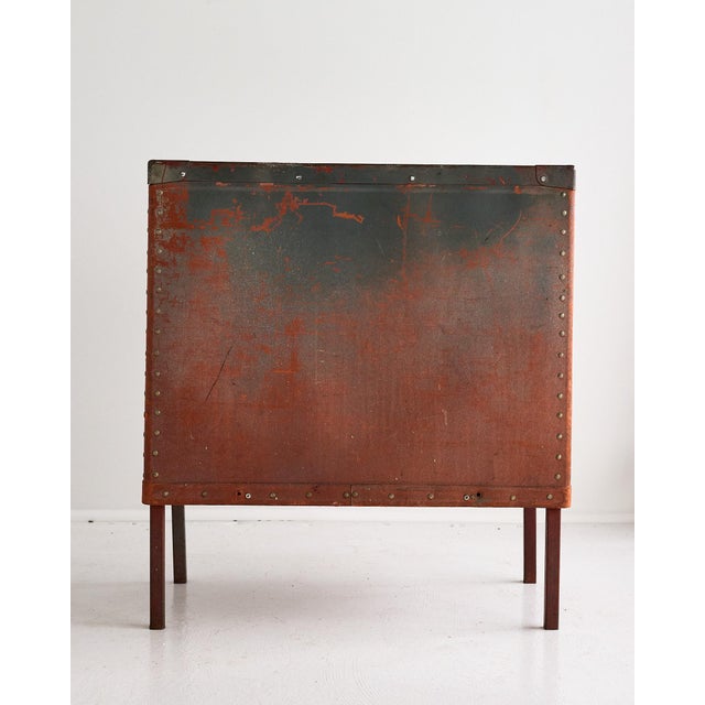 A distinctive vintage hamper clad in a strong and durable leather-like material, possibly parchment, elevated on slender...