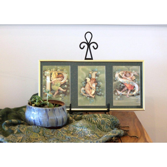 A nicely framed set of vintage postcards, featuring cherubs playing around foil print letters, surrounded by flowers. Each...