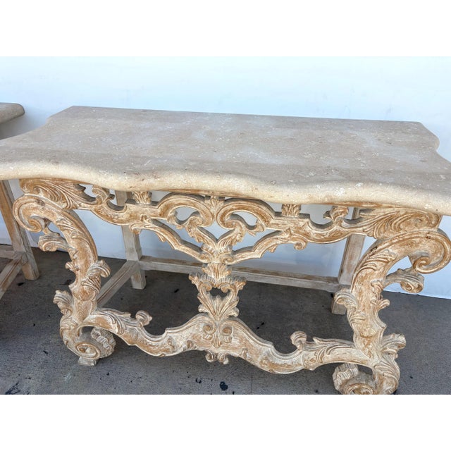A pair of stone top console tables with a carved wood base