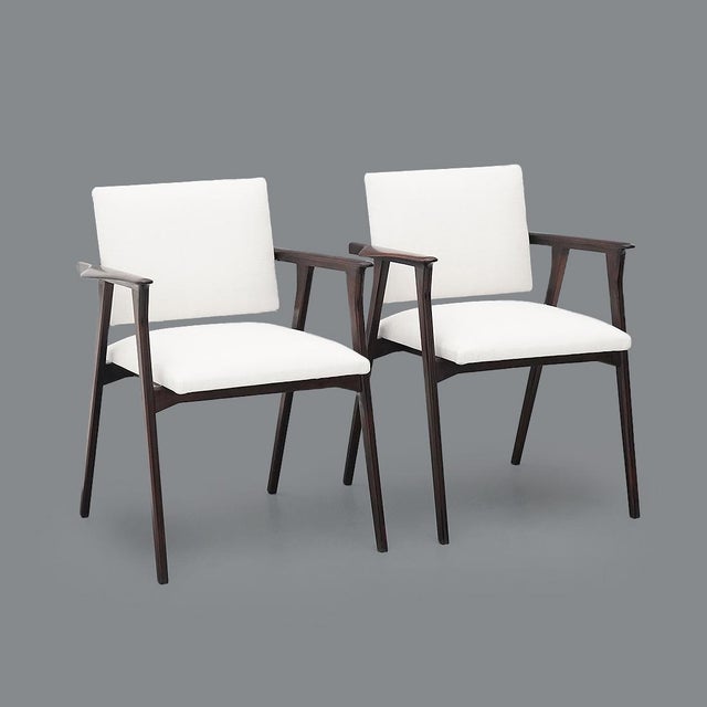 Pair of armchairs produced in the 1950s, featuring a solid wood structure with shaped armrests and light, well-balanced...