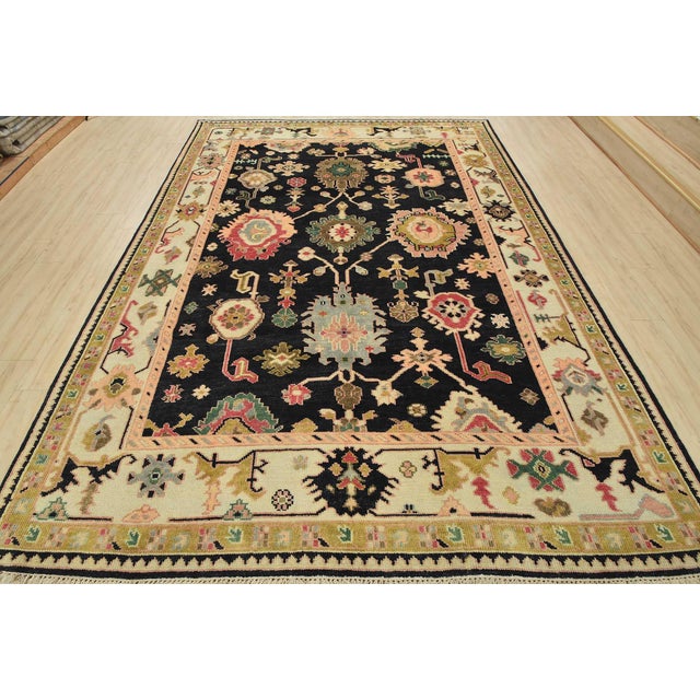 A traditional Oushak rug hand-knotted with an all-wool pile on a cotton foundation. This oriental rug features an all-over...