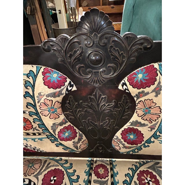 Characterful antique Victorian style carved dark wood loveseat updated with multicolored antique Suzani textile...