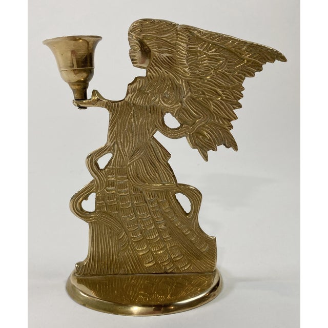 Vintage detailed brass angel figure with robes and hair blowing in the wind. Angel holds a single candlestick. Patina.
