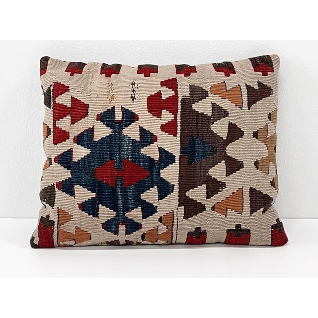 Handcrafted decorative pillow made from a vintage handwoven Turkish kilim, featuring a striking geometric tribal design in...