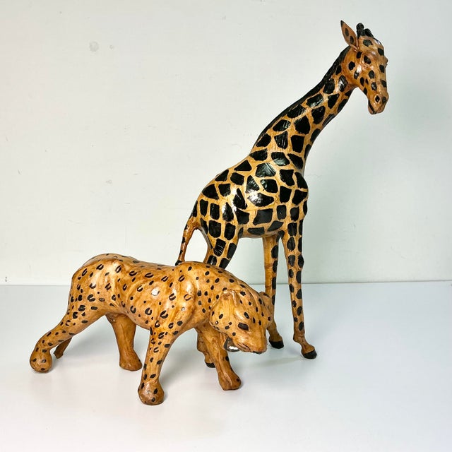 Offering a dramatic pair of safari leather wrapped wild animals. The pair is a Giraffe and Leopard tabletop figurines from...