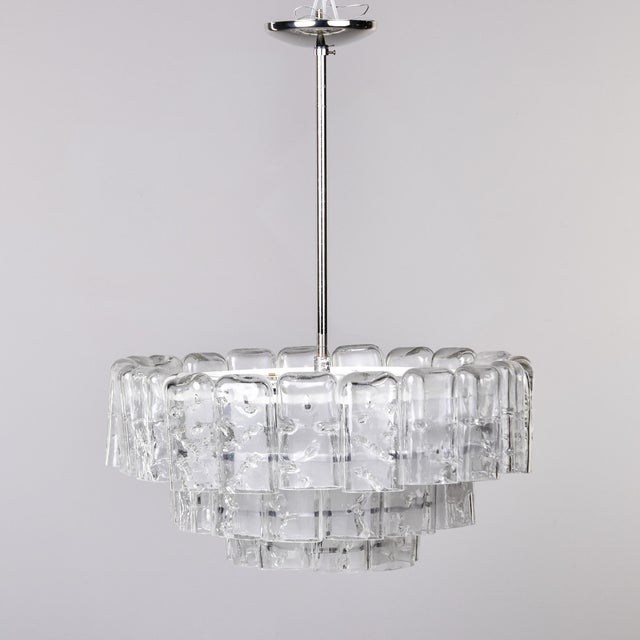 This pair of three tier modernist chandeliers by German maker Doria dates from the 1960s. Chandliers have metal frames...