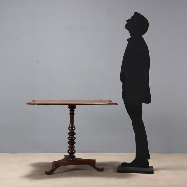 Small table. Top veneered in walnut burl, supported by a turned central leg, resting on a three-legged mahogany base....