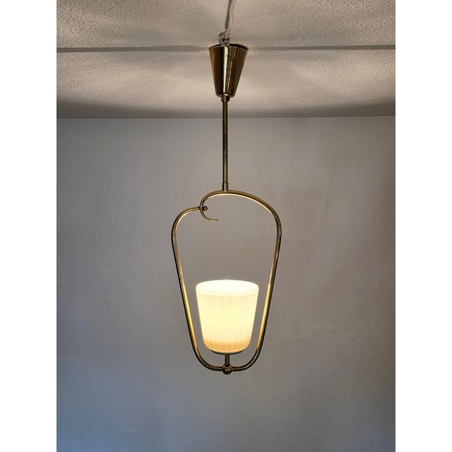 Exceptional vintage pendant light with an elegantly curved, sculptural brass frame. The delicate construction forms a...