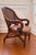 An vintage British Colonial–style armchair featuring a bentwood and rattan frame with hand-woven cane back and sculptural...