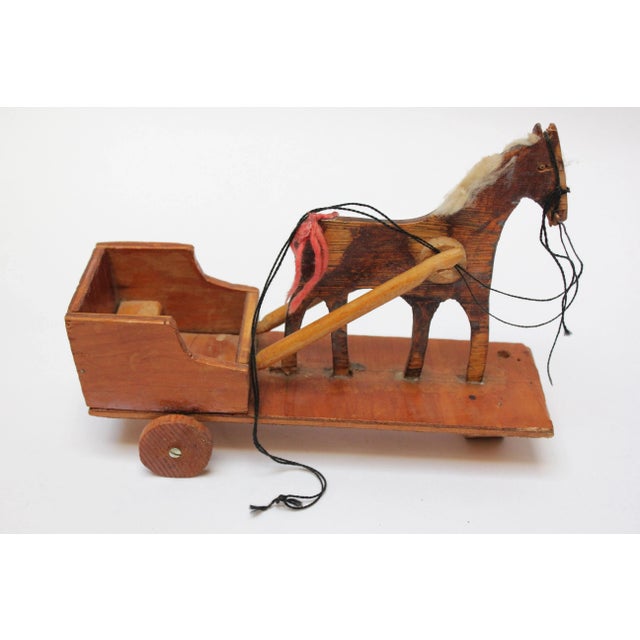 Ca. 1930s/1940s primitive carved wooden horse pulled cart with string reins, a cotton mane, and inset glass eyes. Crude...