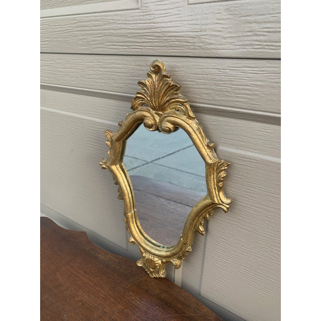 An Italian Rococo–style giltwood wall mirror, richly carved with scrolling acanthus and shell motifs that give the piece...