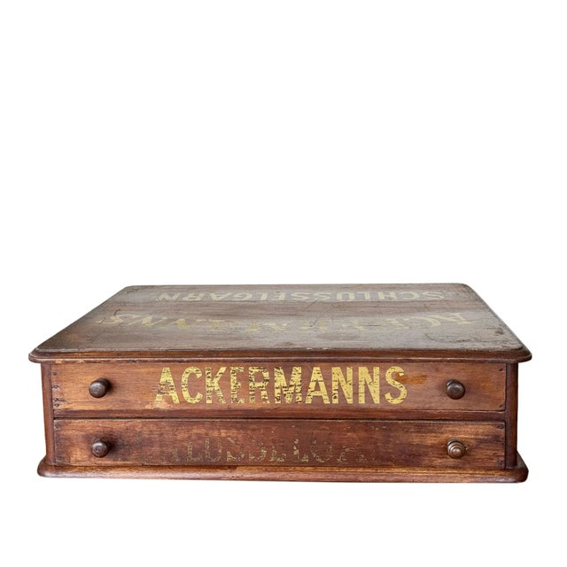 A 19th century German spool cabinet. Cabinet with two drawers with gold writing on the top and drawers that reads...