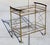 Elegant and eye-catching vintage bar cart featuring a brass frame, two glass shelves, and gracefully curved wooden...