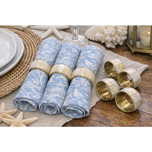 Bring a warm, luminous glow to your table with this set of eight vintage mother‑of‑pearl and brass napkin rings, each...