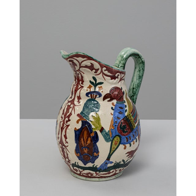 20th Century German Ceramic Vase. This vividly hand-painted ceramic pitcher features a whimsical design with colorful...