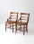 A charming pair of antique Victorian cane-seat chairs, distinguished by their graceful ladder backs, gently arching side...