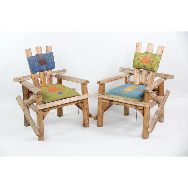 Pair of vintage primitive Adirondack captain's chairs. Handcrafted from natural split round logs, these structurally rock-...