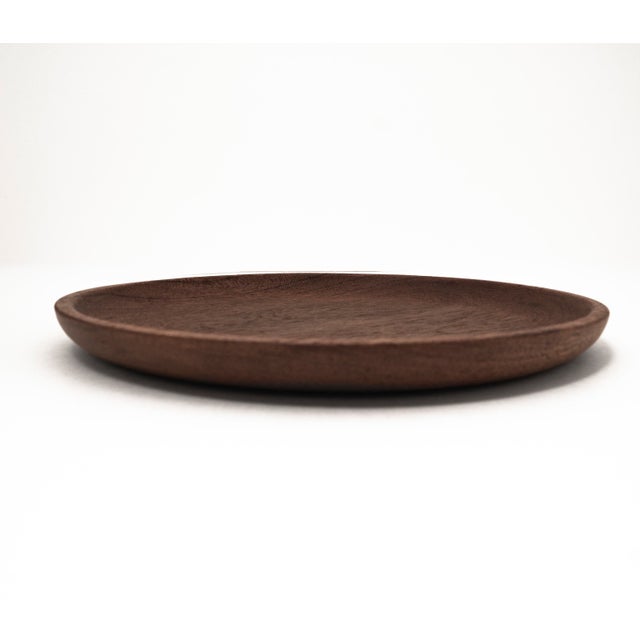 This flat, round wooden bowl dates back to the 1960s and is crafted in the typical Mid Century style. The bowl is made of...