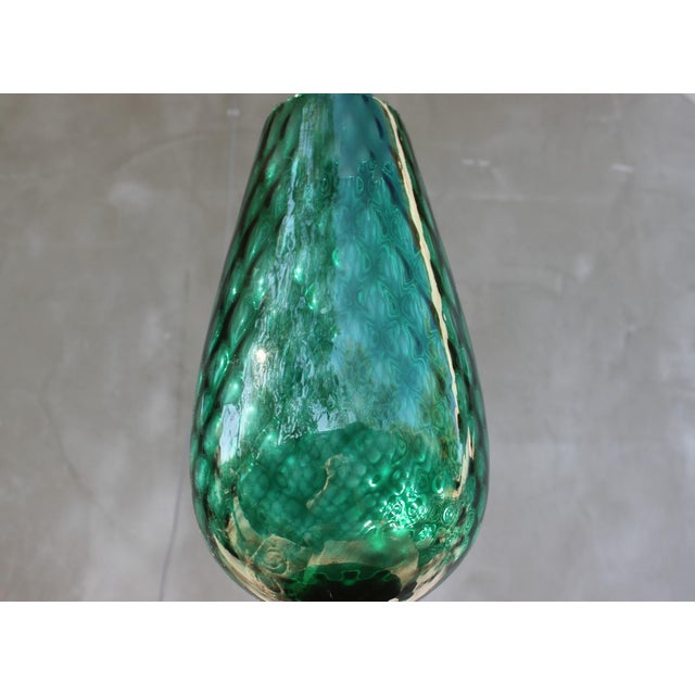 This elegant hand-blown art glass vase is distinguished by its elongated, tulip-inspired silhouette and luminous emerald...