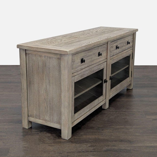 This Pottery Barn media console features a rustic wood finish, two spacious drawers, and two glass-front cabinets with...