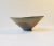 This organically shaped footed stoneware bowl with earthy glazes has a ribbed rim and an abstract centre-motif. The bowl...